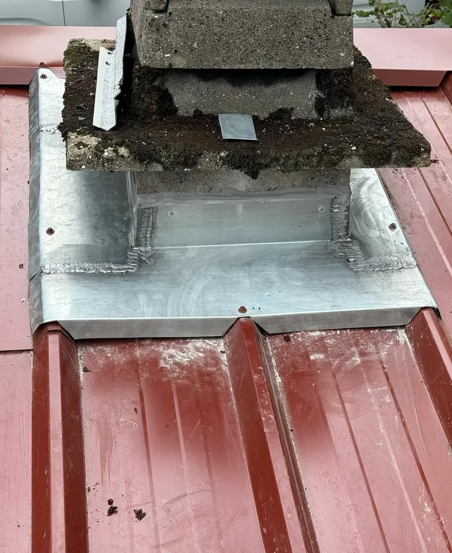 Couverture en bac acier rouge avec habillage zinc autour de la cheminée