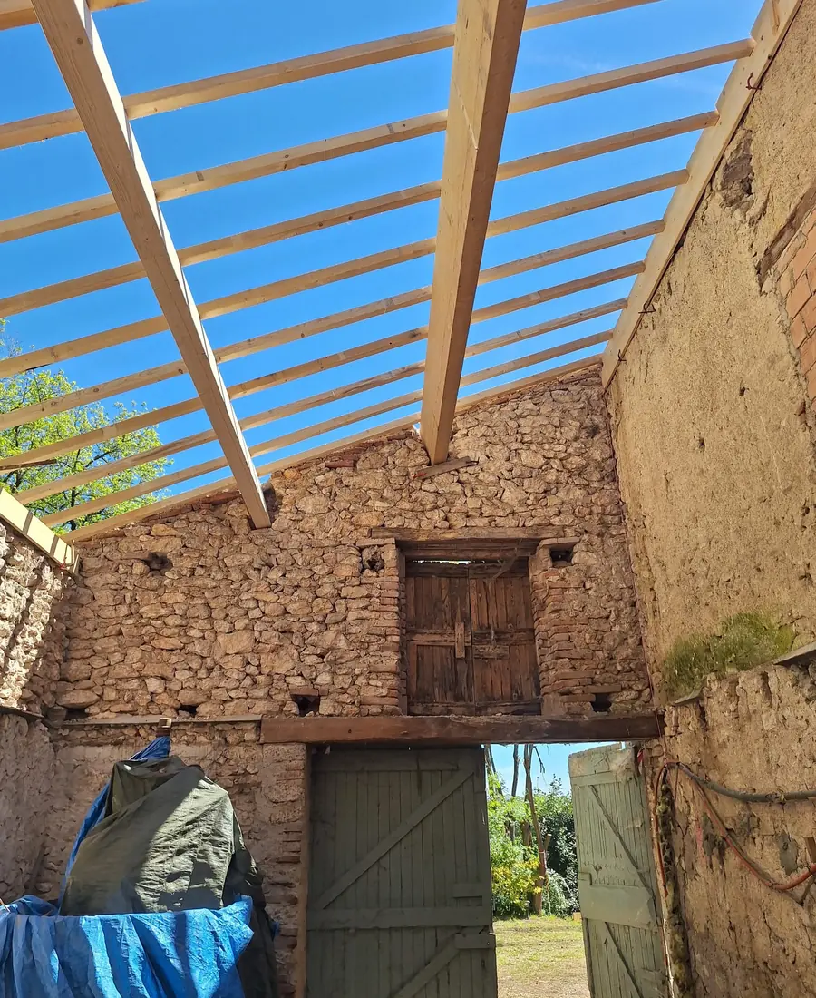 Charpente neuve en chevrons de bois posée sur une grange en pierre